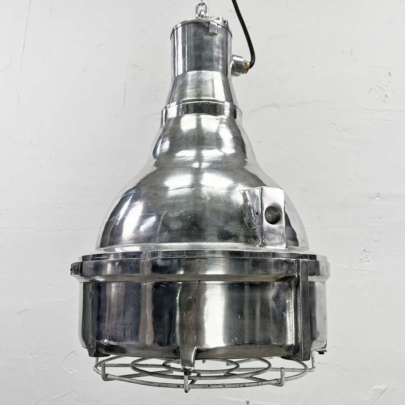 The large explosion proof cast aluminium pendant light was made by the Indian company Baliga Lighting Equipments Ltd. It is a very heavy solid metal light fixture which features a cage over the tempered glass lens that protects the lamp holder from external elements.&nbsp;