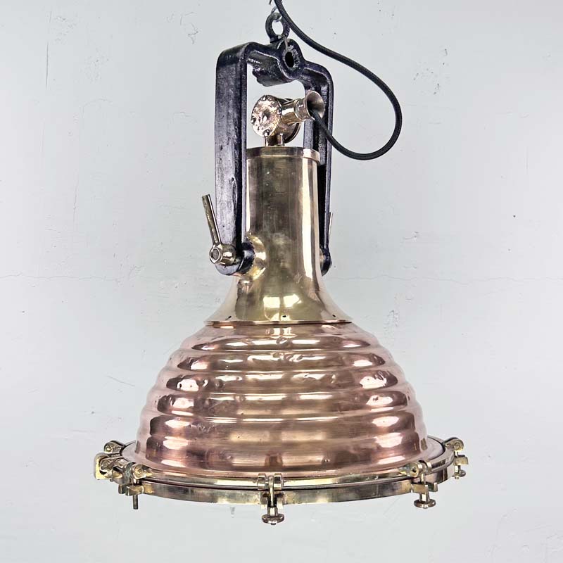 This is a large vintage industrial copper and brass industrial cargo ceiling light made by the German manufacturer Wiska. It consists of a fluted spun copper dome with cast brass top section . It has wing nuts on the hanging mount so that the light can be tilted and illumination directional.