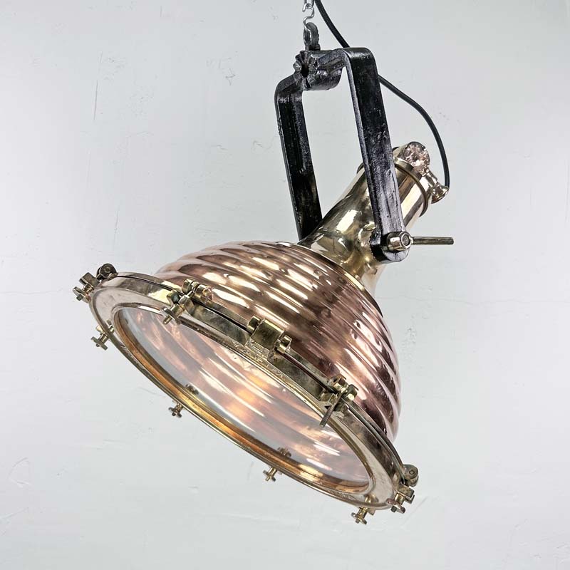 This is a large vintage industrial copper and brass industrial cargo ceiling light made by the German manufacturer Wiska. It consists of a fluted spun copper dome with cast brass top section . It has wing nuts on the hanging mount so that the light can be tilted and illumination directional.