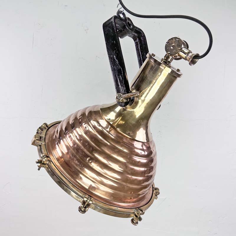 This is a large vintage industrial copper and brass industrial cargo ceiling light made by the German manufacturer Wiska. It consists of a fluted spun copper dome with cast brass top section . It has wing nuts on the hanging mount so that the light can be tilted and illumination directional.