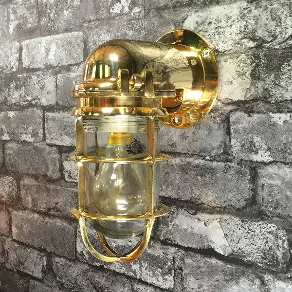 Japanese brass wall light with glass dome and protective cage.