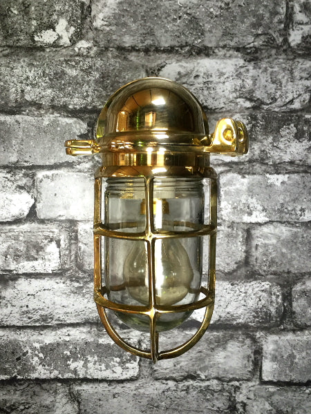 Japanese brass wall light with glass dome and protective cage.