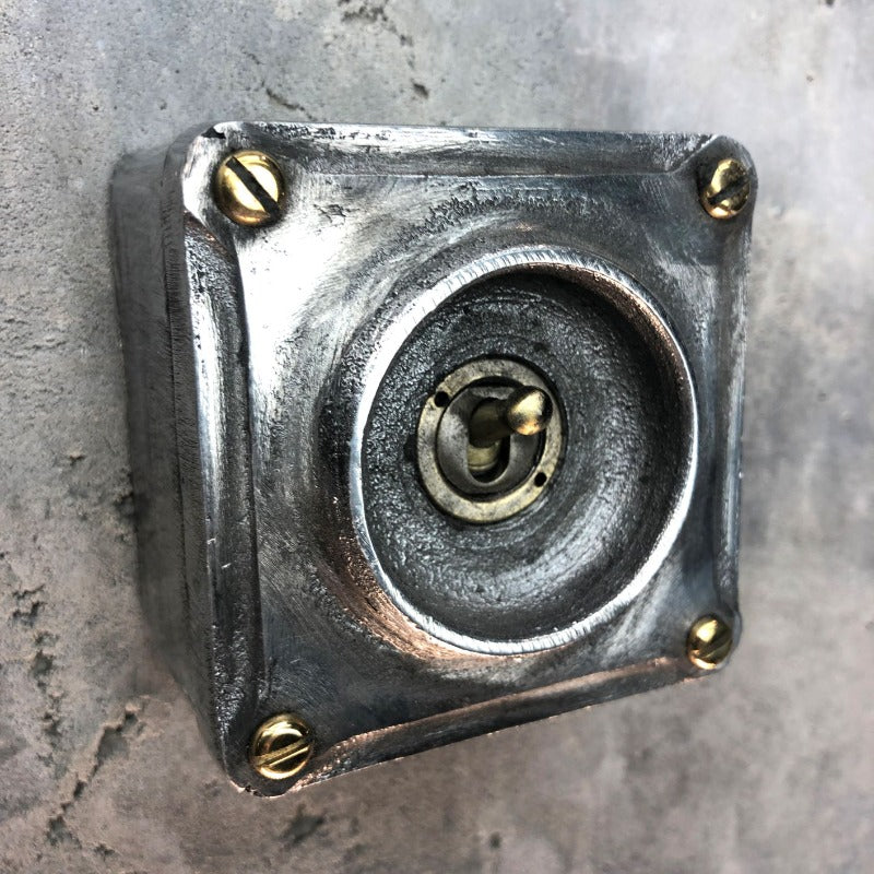 A single industrial light switch.  Manufactured from recycled alloy wheels.